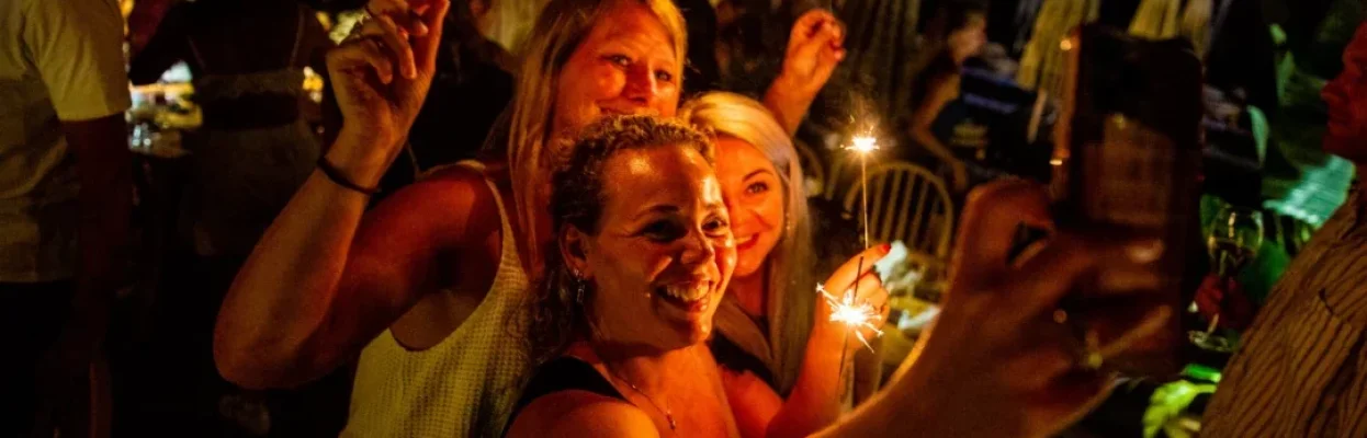 Drie reisgenoten maken samen een selfie met sterretjes tijdens een feestelijke avond.