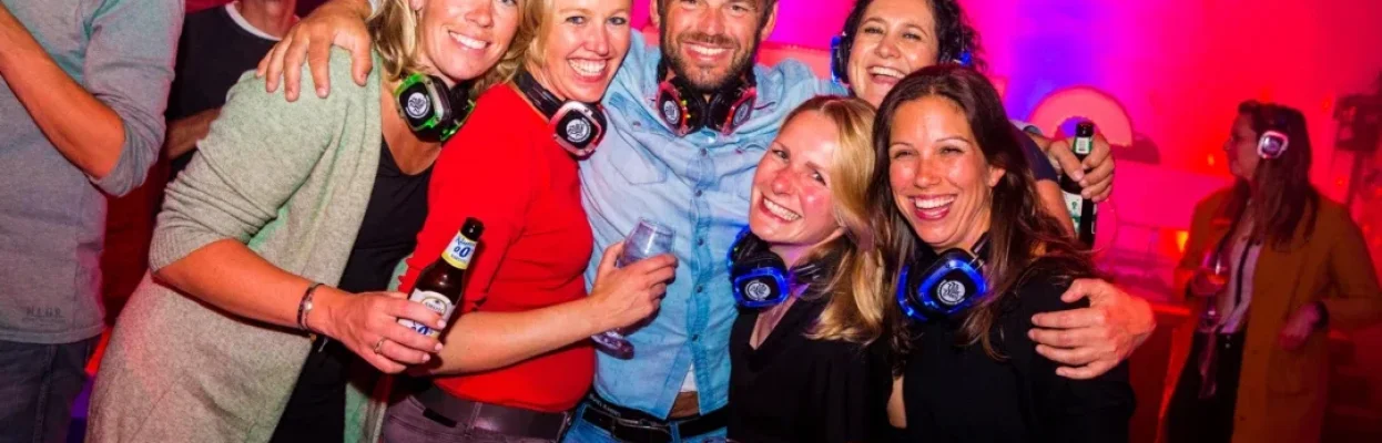 Groep reisgenoten poseert lachend met koptelefoons tijdens een silent disco.