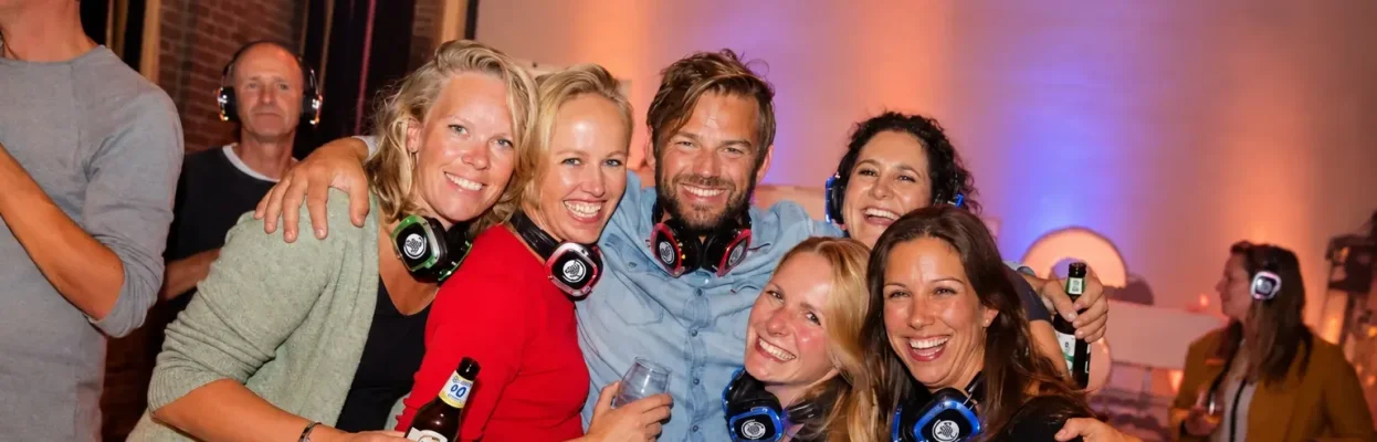 Groep reisgenoten poseert lachend met koptelefoons tijdens een silent disco.
