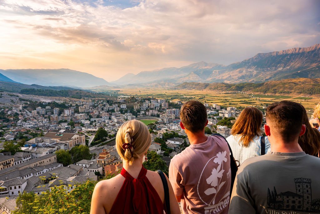 Reisgenoten kijken samen uit over een stad en bergachtig landschap tijdens een rondreis.
