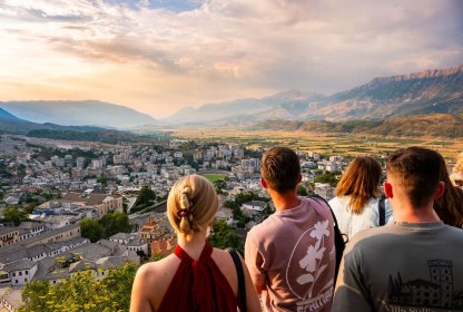 Reisgenoten kijken samen uit over een stad en bergachtig landschap tijdens een rondreis.