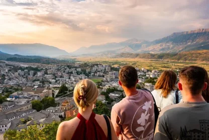 Reisgenoten kijken samen uit over een stad en bergachtig landschap tijdens een rondreis.