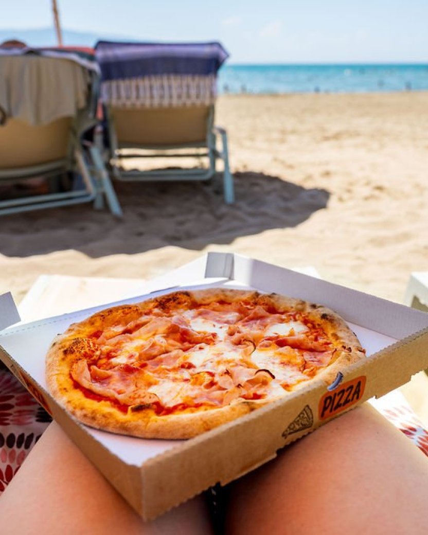 Pizza op het strand met uitzicht op zee tijdens een ontspannen stranddag.