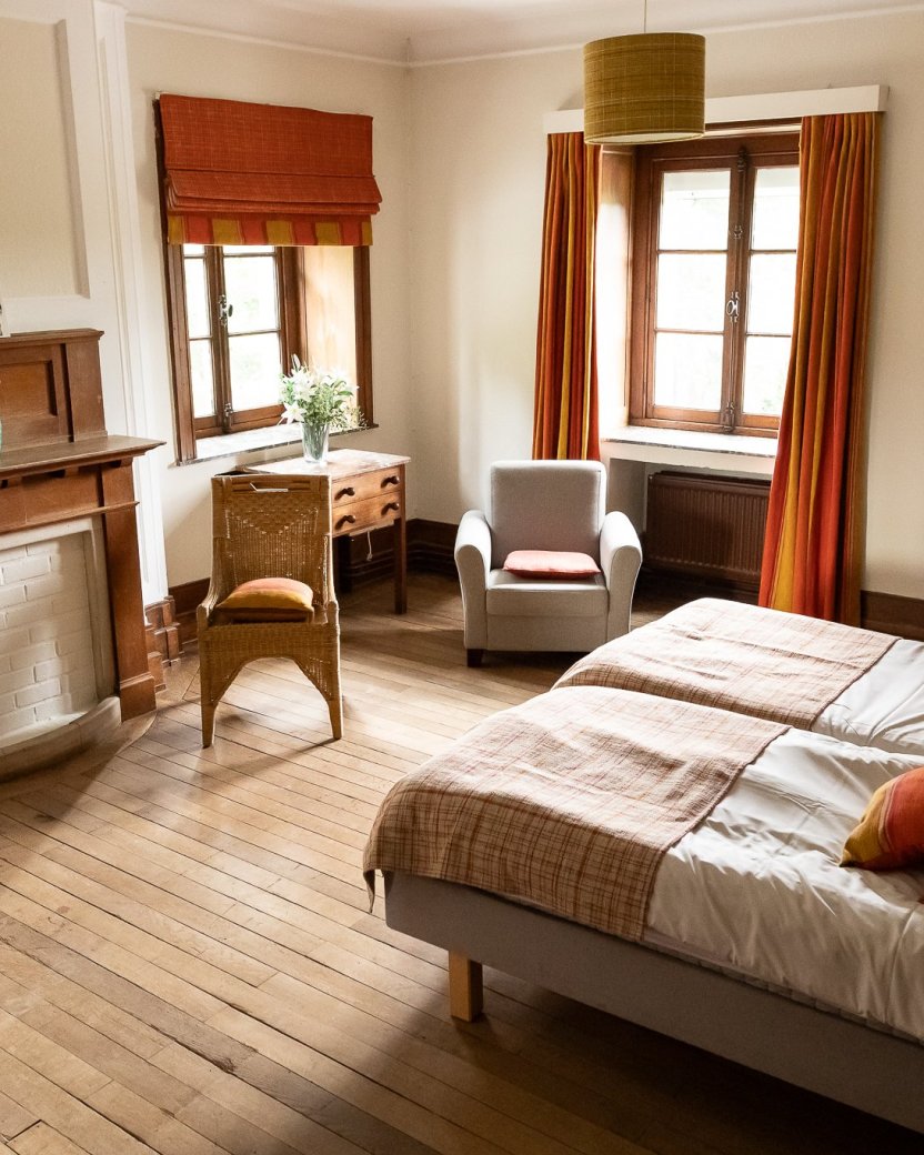 Ruime slaapkamer met twee bedden en zithoek in het landhuis.