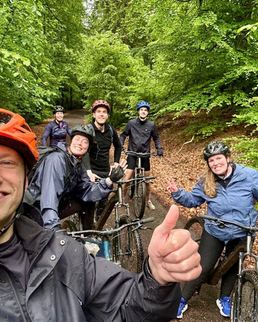 Groep reisgenoten poseert met mountainbikes tijdens een tocht door het bos.