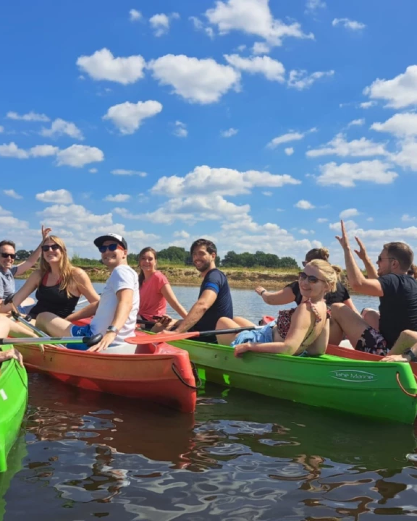 Groep reisgenoten vaart samen in kano’s over het water op een zonnige dag.