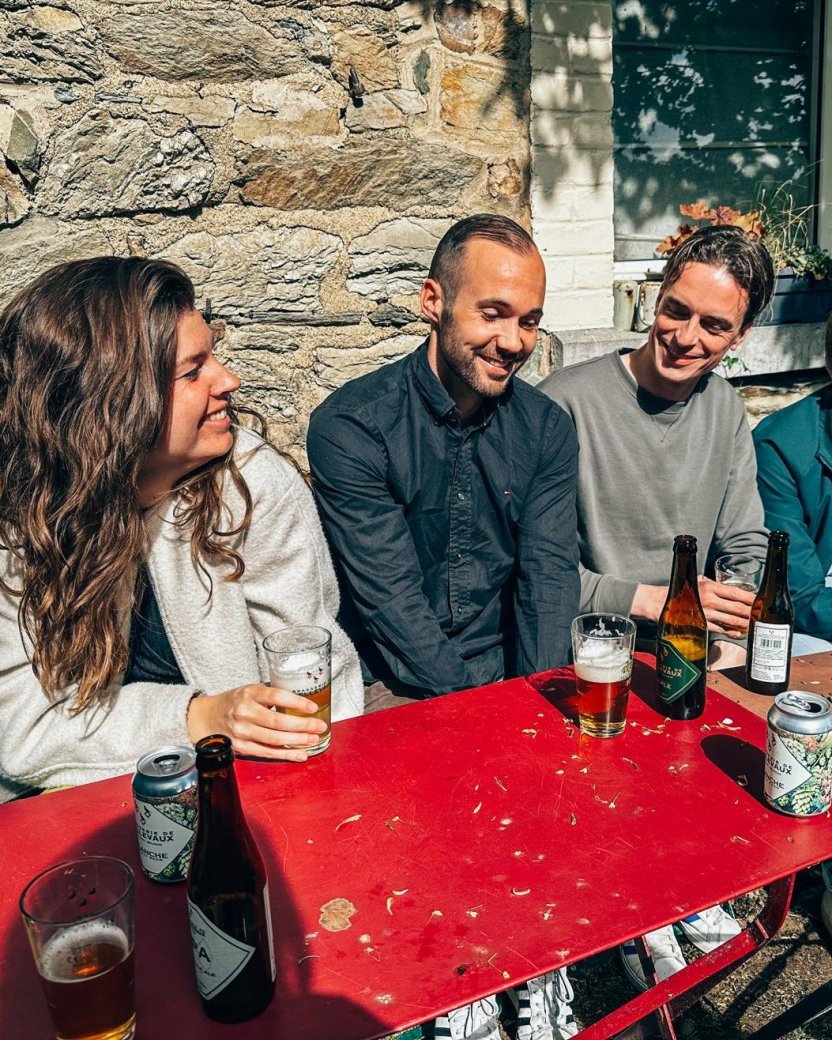 Vier reisgenoten zitten samen buiten aan tafel met een drankje.