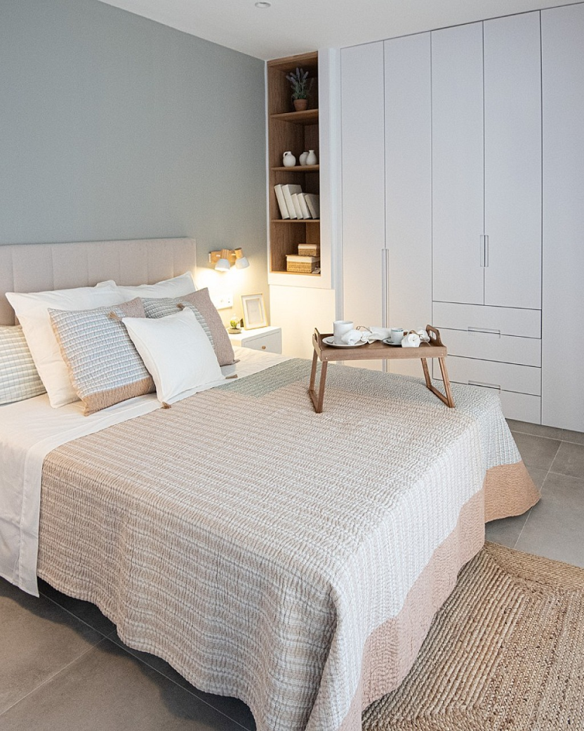 Lichte moderne slaapkamer met groot bed en veel kastruimte.