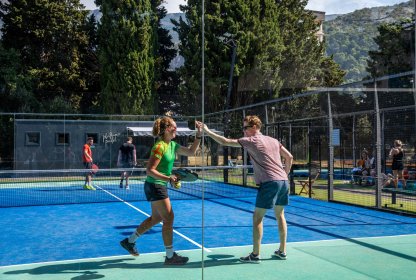 Padellers geven elkaar een high five na winst op de padelbaan.