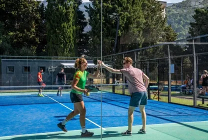 Padellers geven elkaar een high five na winst op de padelbaan.