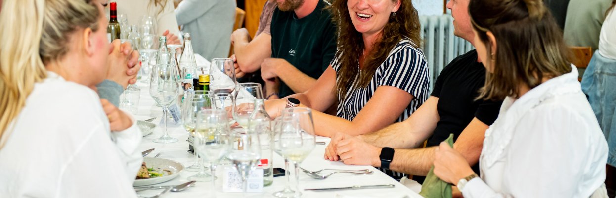 Groep reisgenoten dineert aan een lange tafel met een grote pan paëlla.