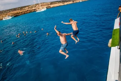 Reisgenoten springen van de boot af het helderblauwe water van Cyprus in.