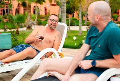 Twee reisgenoten ontspannen samen op ligbedden met een drankje bij het resort.