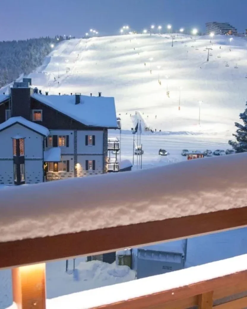 Uitzicht vanaf het balkon van het chalet op de besneeuwde piste.