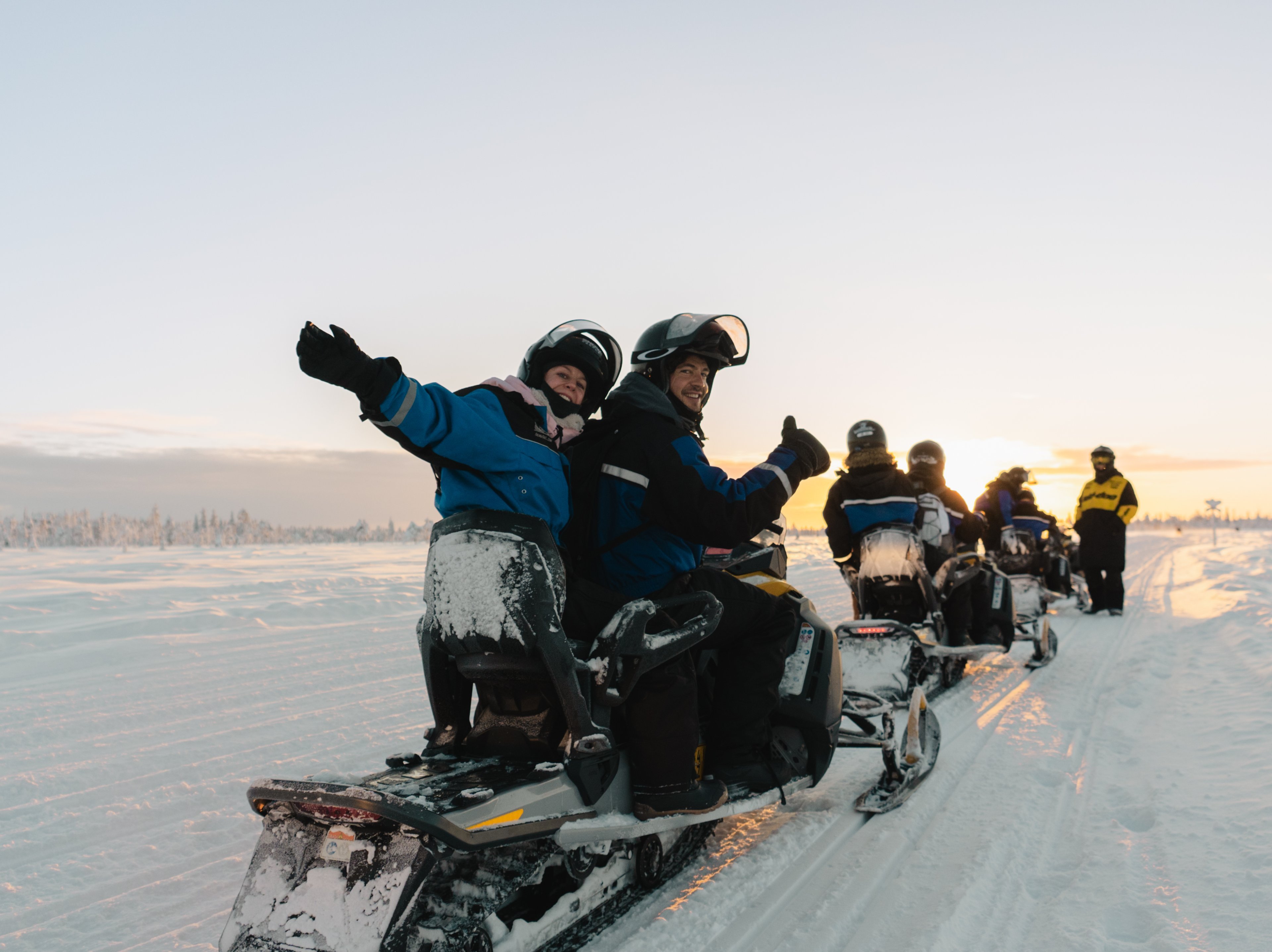 Reisgenoten rijden samen op sneeuwscooters door een besneeuwd winterlandschap.