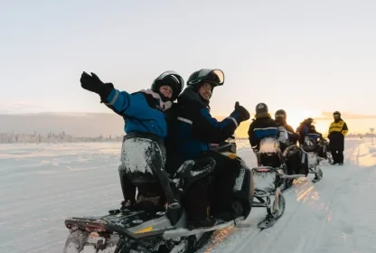 Reisgenoten rijden samen op sneeuwscooters door een besneeuwd winterlandschap.
