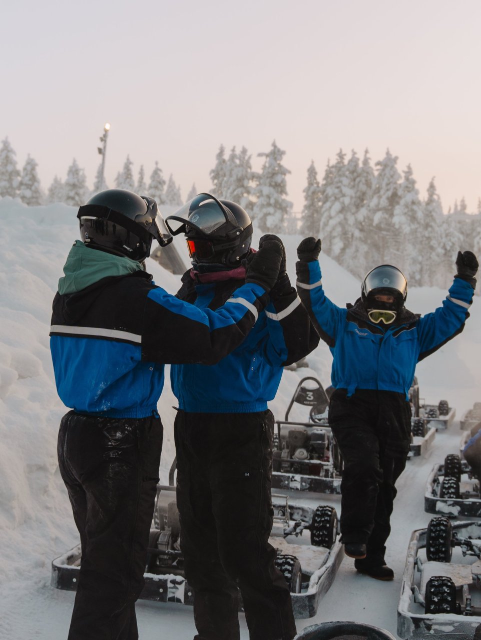 Reisgenoten vieren samen een geslaagde rit naast hun snowkarts in het besneeuwde landschap.