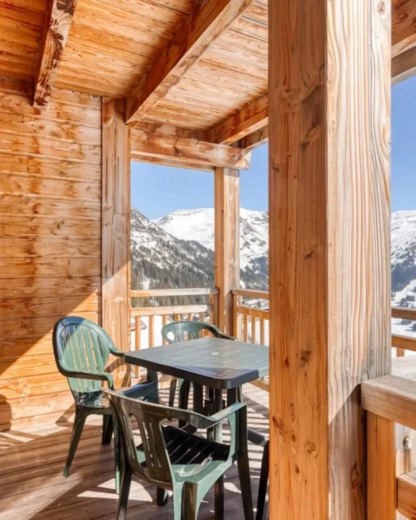 Houten balkon met zitje en uitzicht op de besneeuwde bergen.