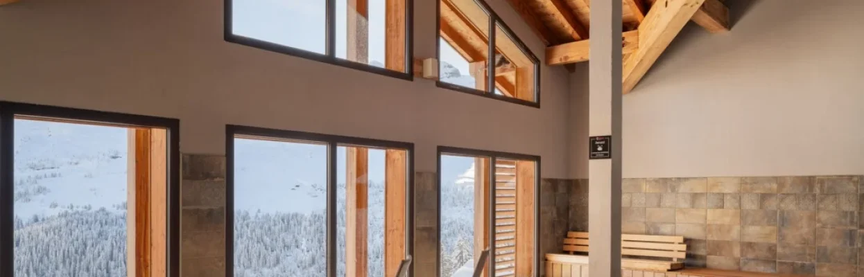 Wellnessruimte met sauna, jacuzzi en uitzicht op het besneeuwde berglandschap.