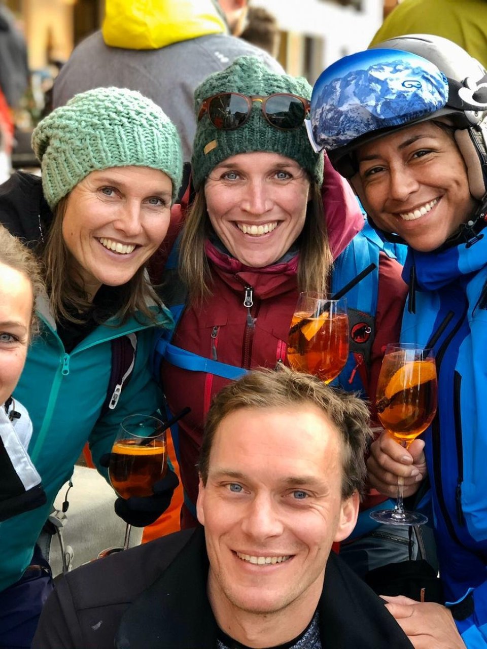 Wintersporters lachen voor de groepsfoto met een drankje in de hand.