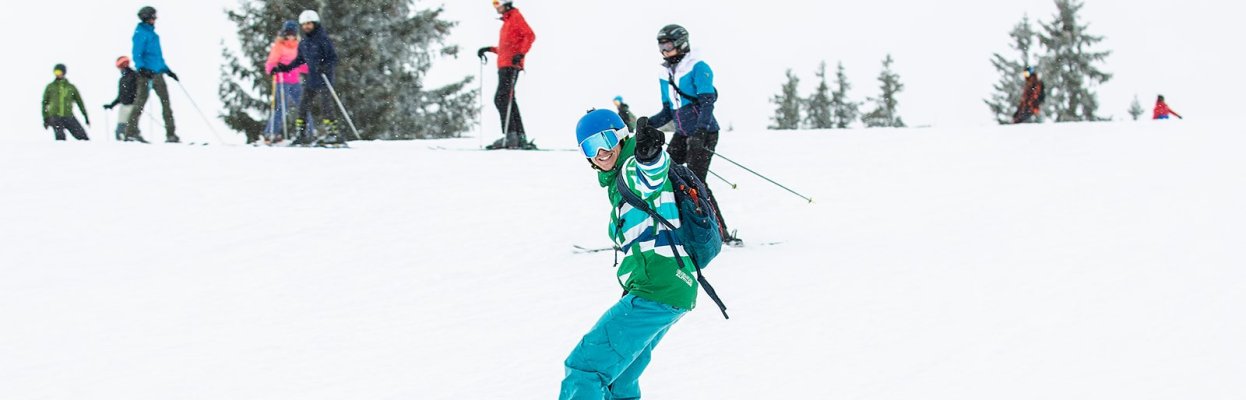 Snowboarder daalt af over een besneeuwde piste met andere wintersporters op de achtergrond.