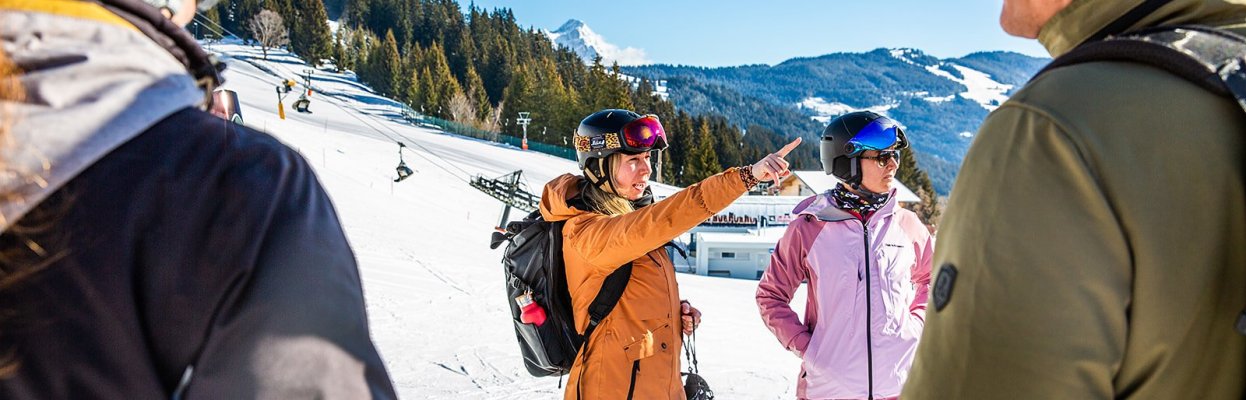 Wintersporters overleggen samen op de piste terwijl één van hen de route aanwijst.