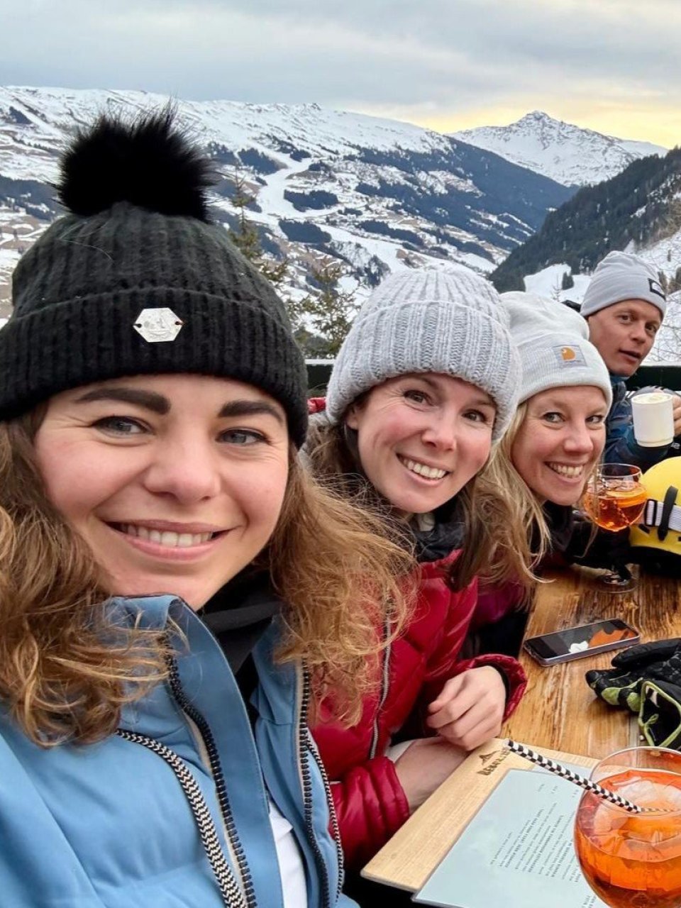Wintersporters proosten samen op een terras aan de piste.