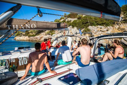 Reisgenoten zitten samen aan boord terwijl de schipper uitleg geeft tijdens de zeiltocht.