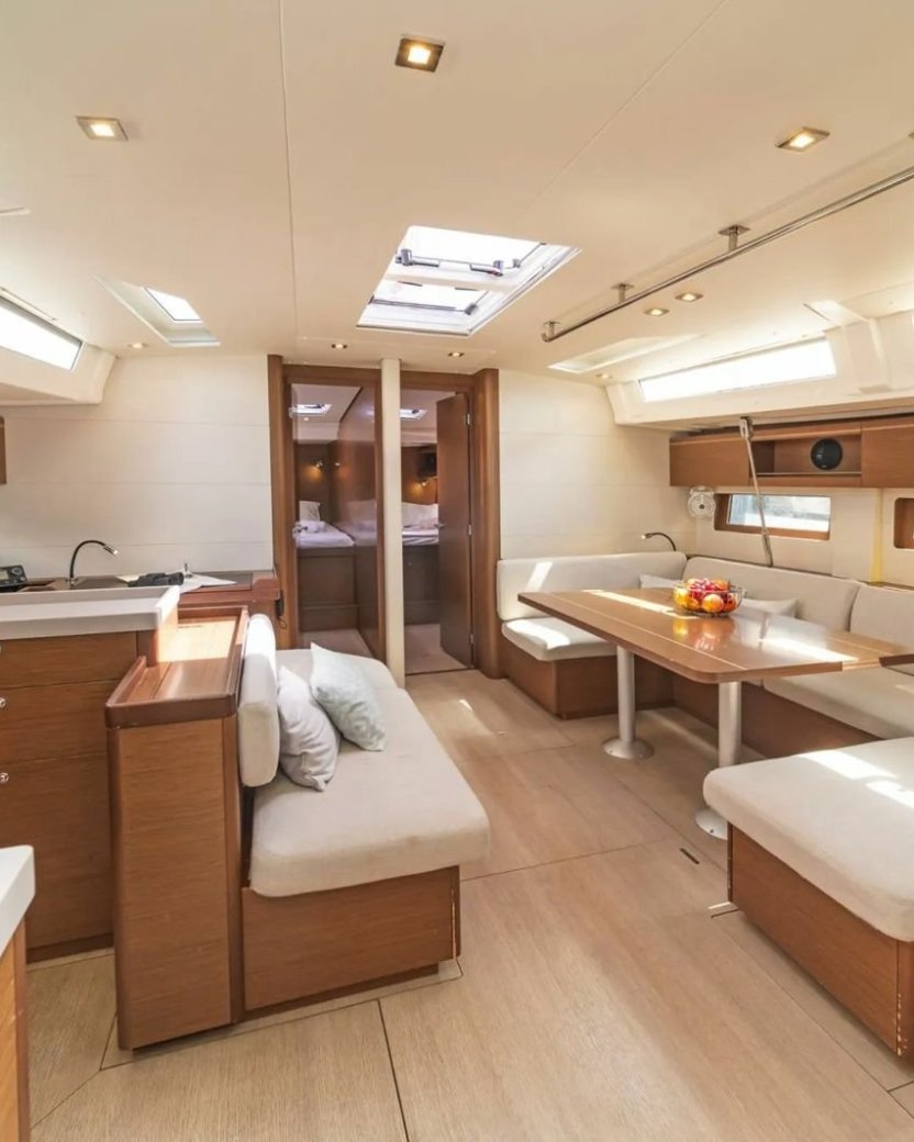 Lichte moderne salon van een zeilboot met keuken, zithoek en eettafel.