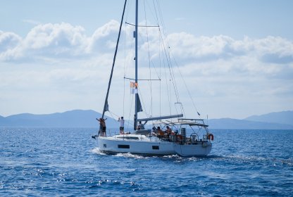 Reisgenoten genieten van het uitzicht vanaf de zeilboot terwijl zij varen op het helderblauwe water.