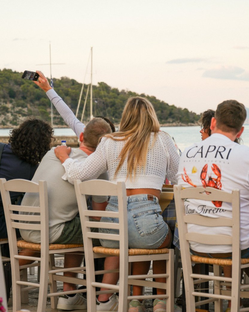 Reisgenoten maken samen een selfie tijdens het diner aan het water.