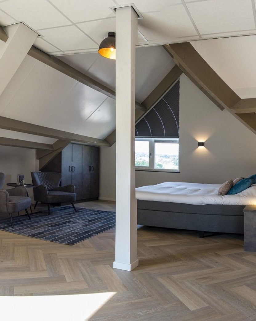 Ruime slaapkamer met bed en zithoek.