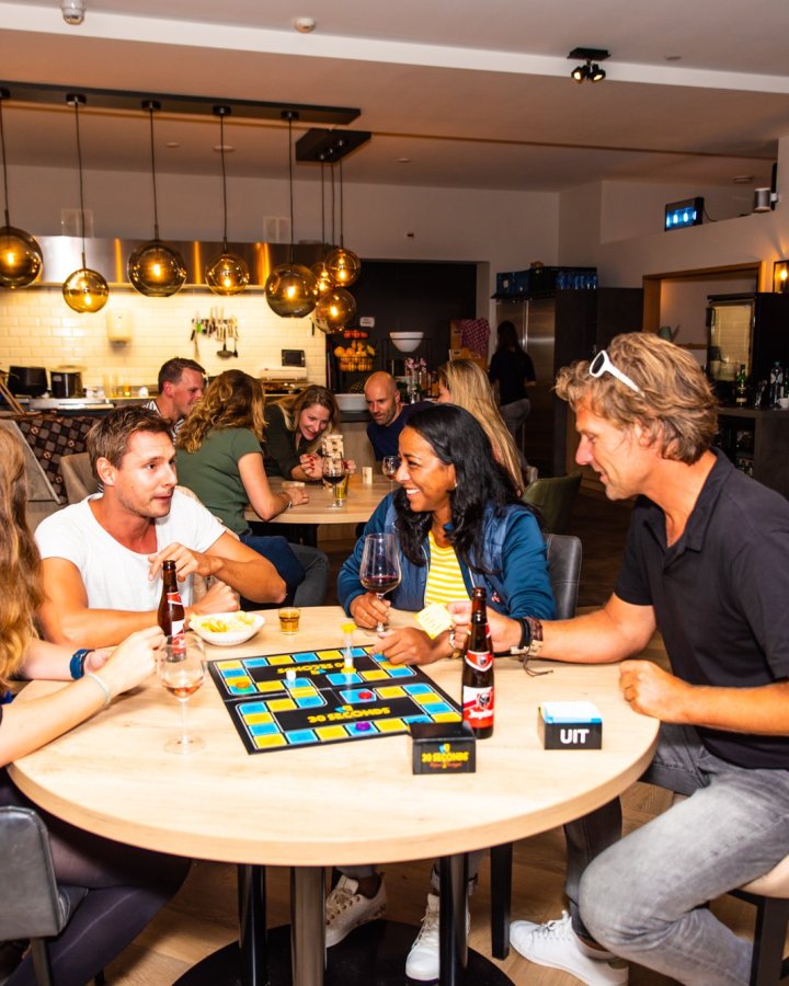 Reisgenoten spelen samen een bordspel aan tafel met drankjes erbij.