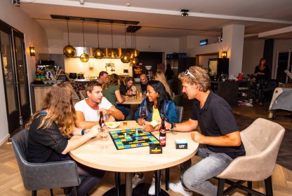 Reisgenoten spelen samen een bordspel aan tafel met drankjes erbij.
