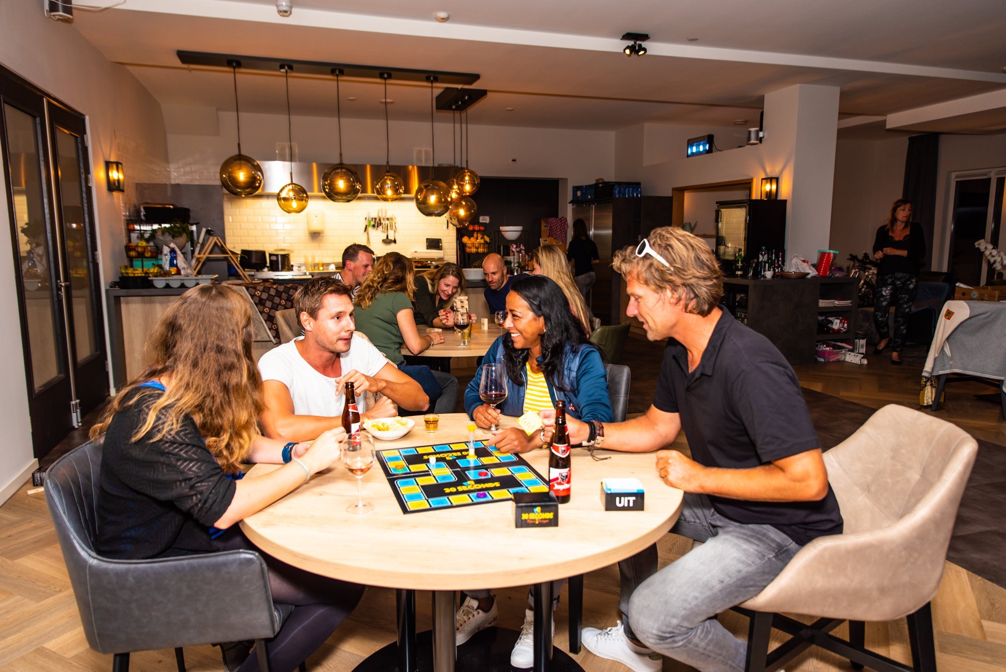 Reisgenoten spelen samen een bordspel aan tafel met drankjes erbij.