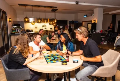 Reisgenoten spelen samen een bordspel aan tafel met drankjes erbij.
