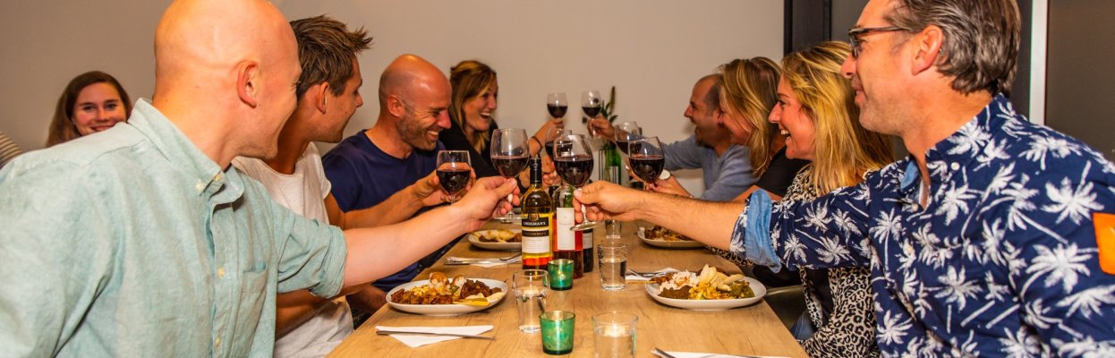 Groep reisgenoten proost samen tijdens het diner.