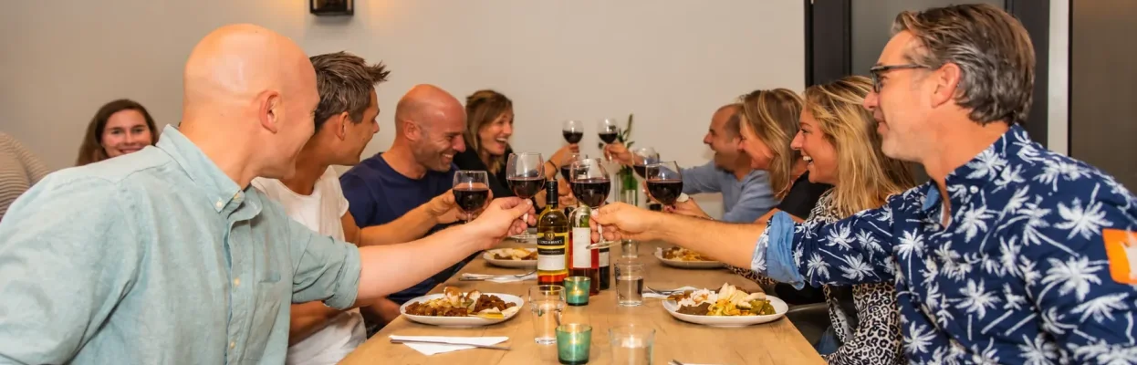 Groep reisgenoten proost samen tijdens het diner.