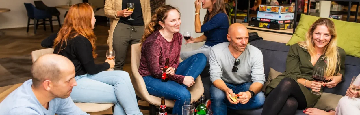 Groep reisgenoten zit samen in de woonkamer met drankjes en hapjes.