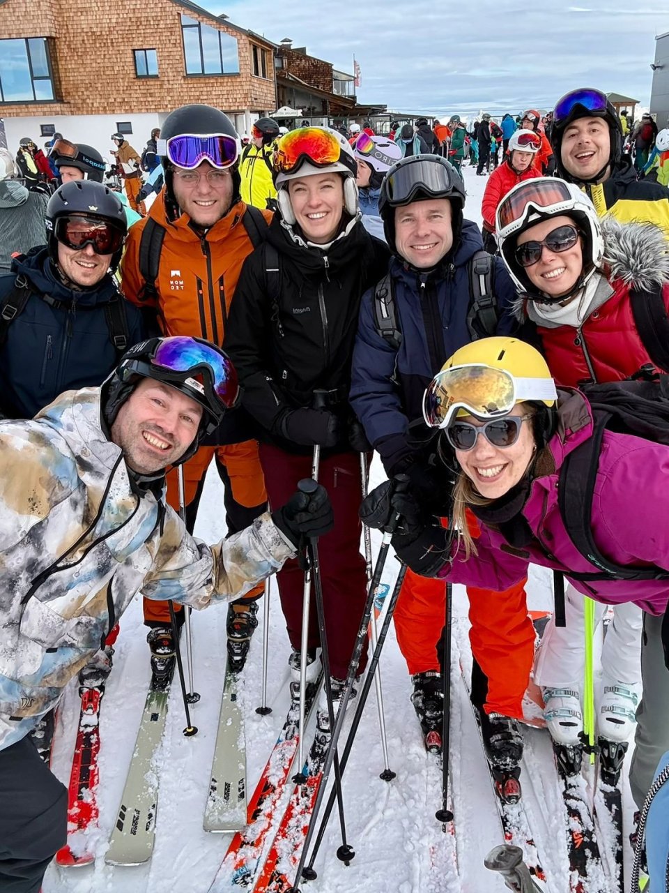 Groep skiërs poseert enthousiast samen bovenaan de piste.