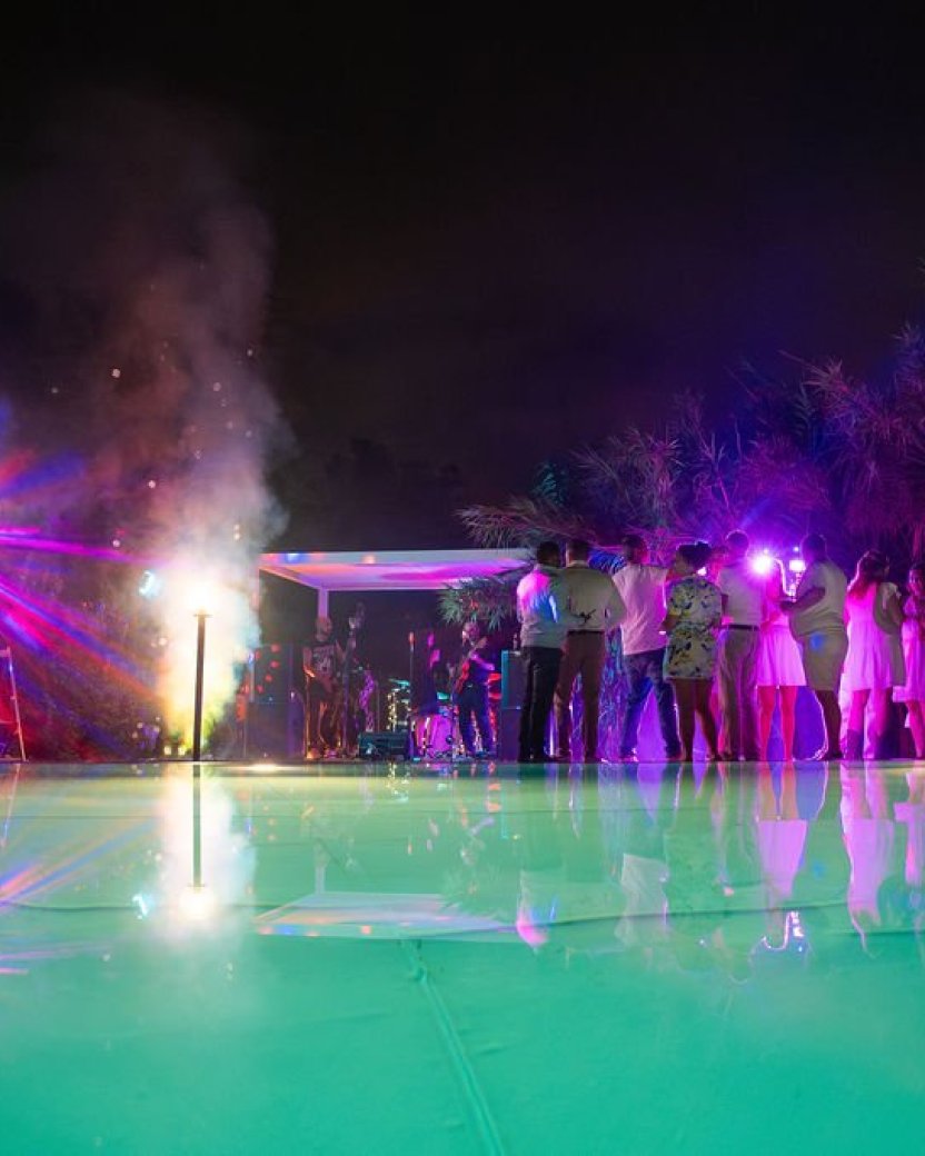 Groep reisgenoten viert samen een feestelijke avond bij het verlichte zwembad.