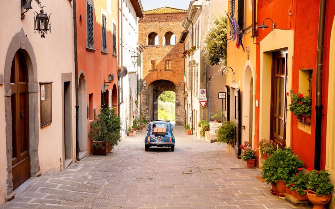 Fiat 500 in een smal straatje door een dorp in toscane.