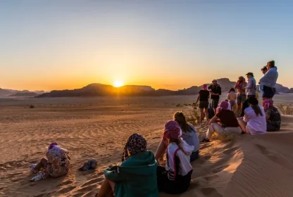 Groep reisgenoten bekijkt de zonsondergang in de woestijn.