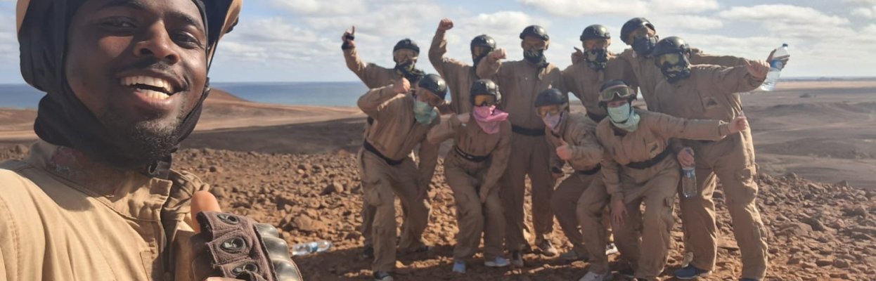 Groep reisgenoten poseert samen met hun gids tijdens een buggytocht door een ruig woestijnlandschap.