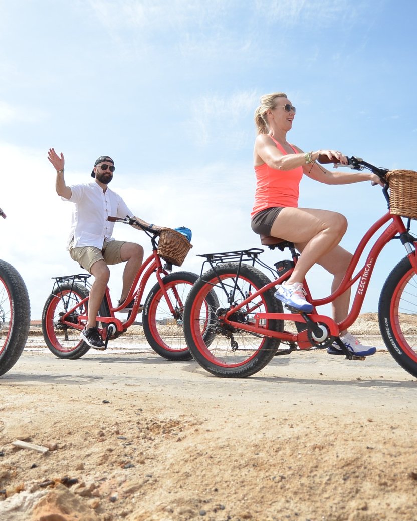 Drie reisgenoten fietsen samen op fatbikes door een zonnig woestijnlandschap.