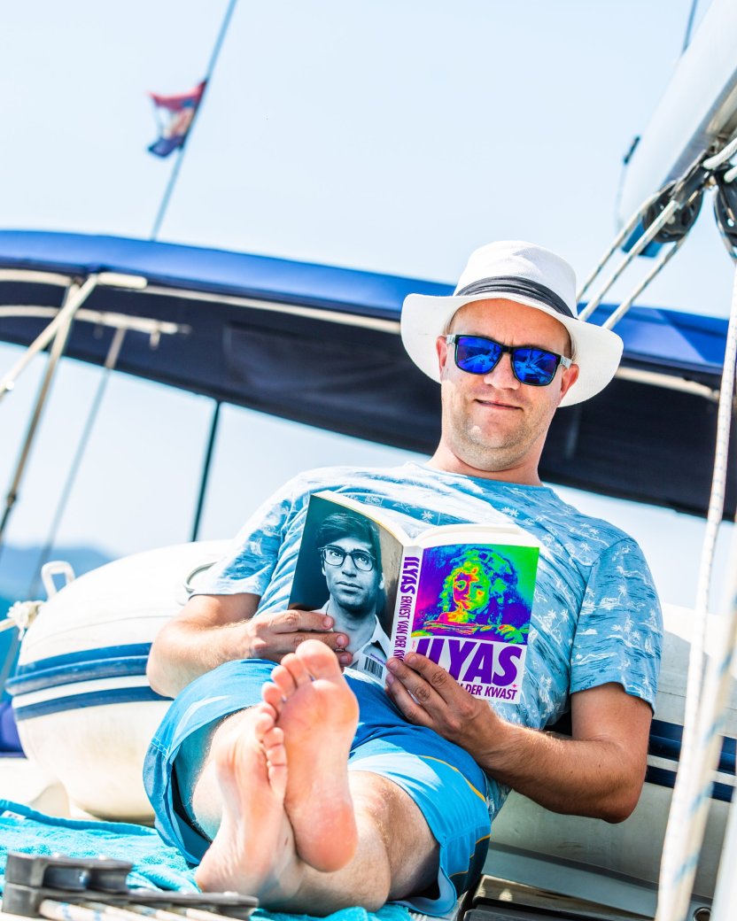 Reisgenoot ontspant op het dek van de boot terwijl hij een boek leest.