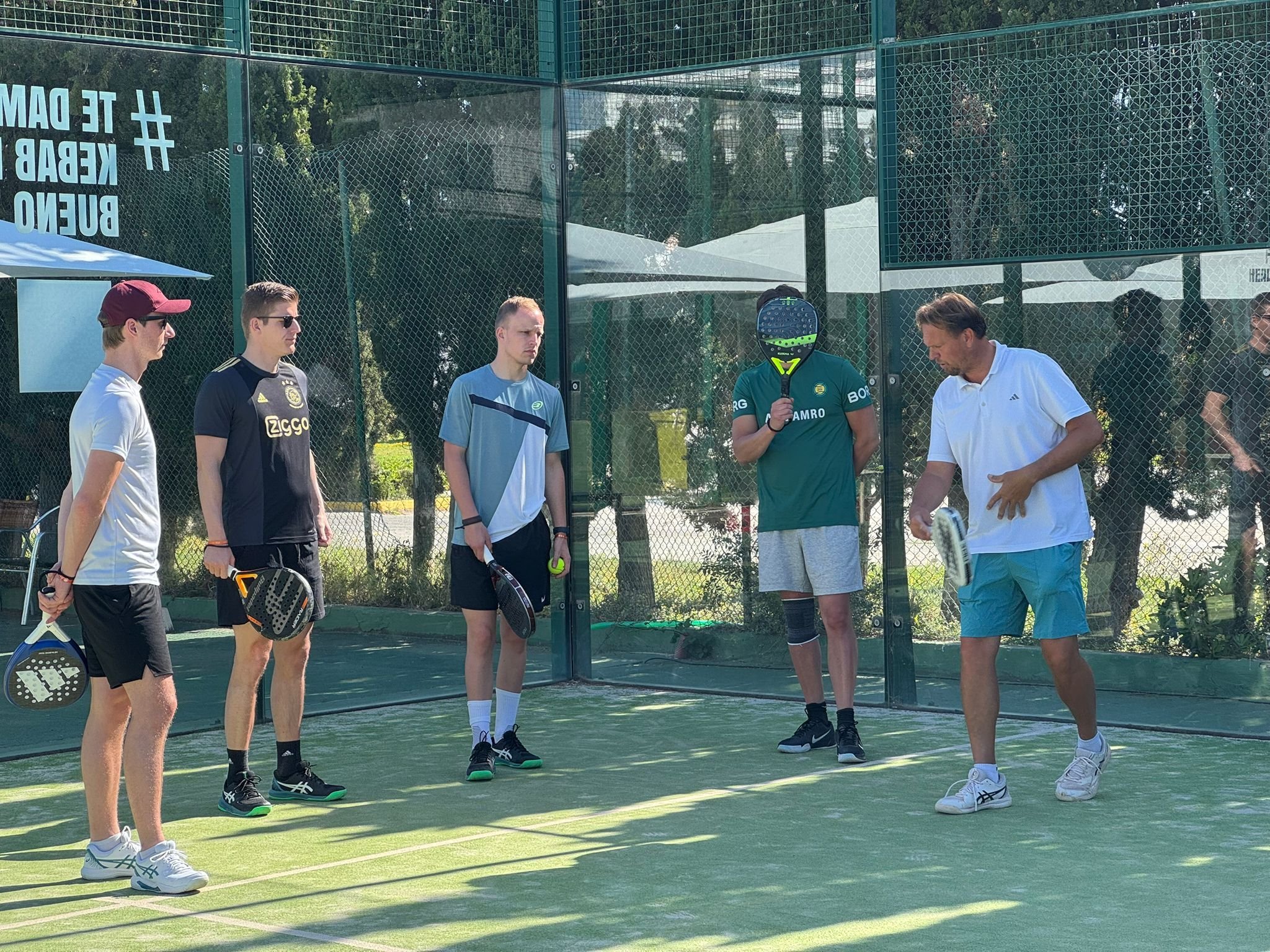 Groep padellers krijgt uitleg over het spel op de padelbaan.