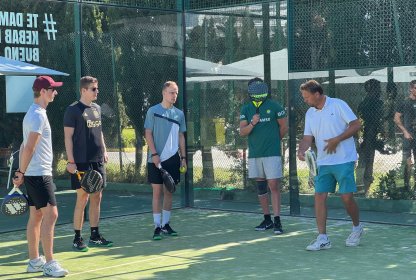 Groep padellers krijgt uitleg over het spel op de padelbaan.