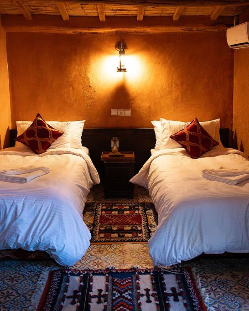 Tweepersoonskamer met twee losse bedden, een airco en warme Marokkaanse inrichting.