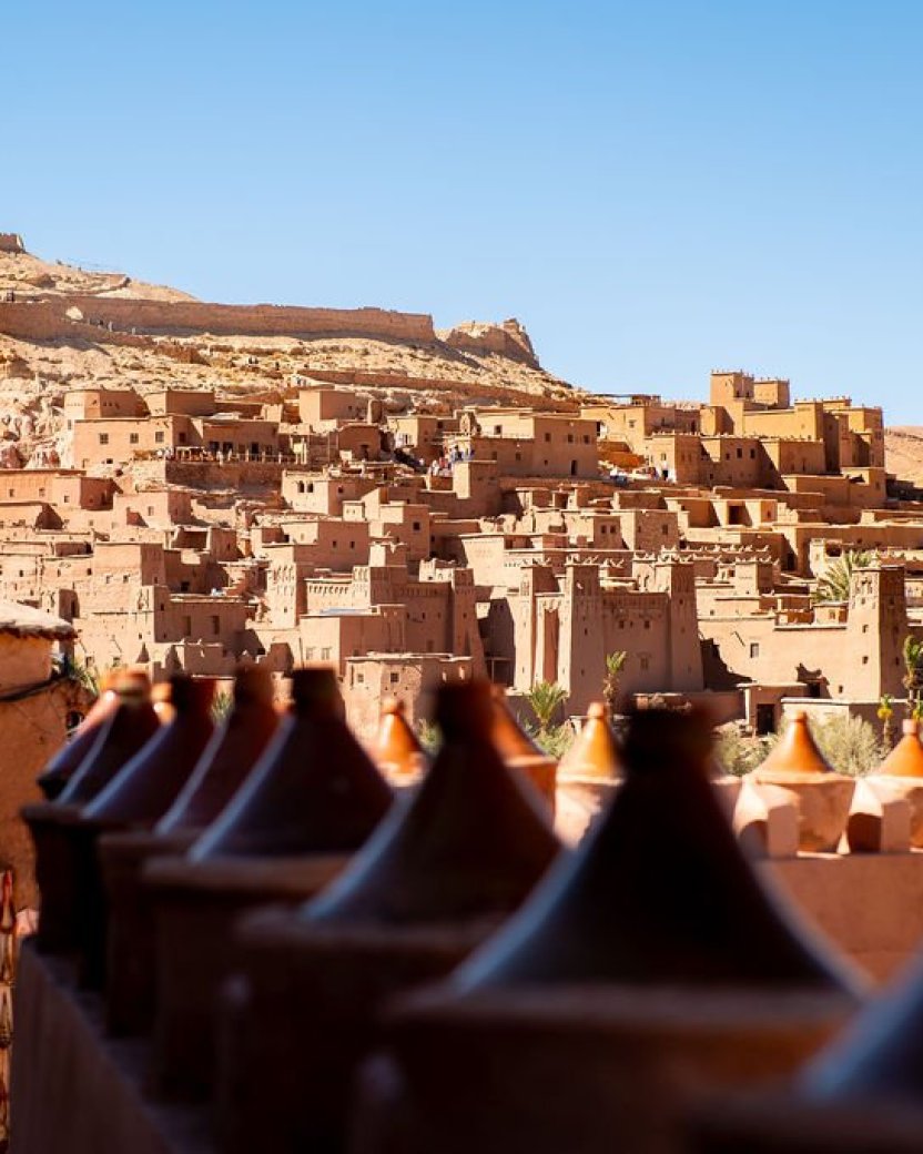 Historisch woestijndorp met lemen gebouwen en een kasbah tegen de heuvels.